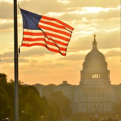 United States Capitol building silhouette and US flag at sunrise - Washington DC