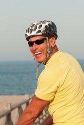 Portrait of a happy smiling active older man with a cycling helmet on a summer evening