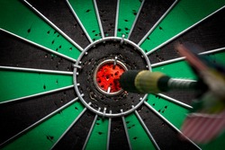 Dart in bulls eye of dartboard with shallow depth of field concept for hitting target