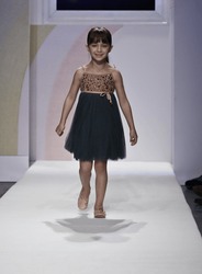 NEW YORK - OCTOBER 21: Girl walks runway petite Parade show by Lamantine Paris during kids fashion week sponsored by Vogue Bambini & Swarovski Elements at Industria Supertudio on Oct 21, 2012 in NYC