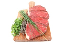 fresh raw red meat with thyme and chives on wooden plate isolated on white background