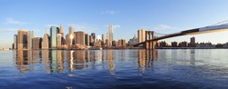 Brooklyn Bridge with lower Manhattan skyline panorama in the morning with cloud and river reflection over East River in New York City