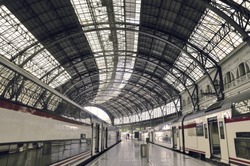 modern train station with waiting railroad cars and arc metallic roof