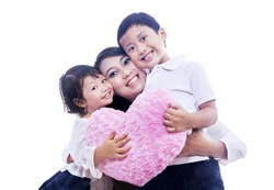 Two happy children is giving their mom a hug while holding pink pillow on isolated white background