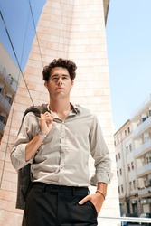 Young aspirational businessman holding his suit jacket over his shoulder in a golden mirror modern office building in the city.