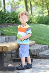 Child outdoors in a park in summer, active and fit, thirsty drinking a juice