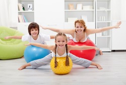 Happy kids exercising with their mother using large rubber balls
