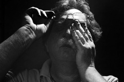 tired middle-aged man rubs his eyes< black and white
