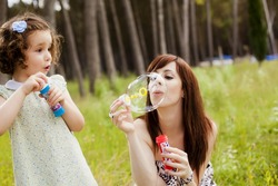 Young mother and her child playing with soap bubbles