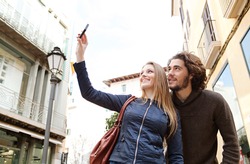 Young tourist couple visiting a destination city and taking pictures of the classic buildings while on vacation in Europe.