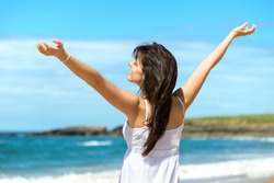 Joyful happy woman raising arms to the sky on summer. Beautiful and blissful caucasian girl on beach vacation. Playa de Verdicio, Asturias, Spain.
