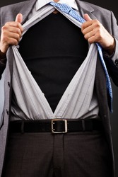 Conceptual image of a businessman tearing off his shirt over gray background