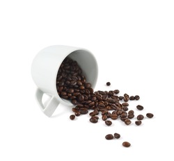 Spilled coffee beans from the white ceramic cup isolated over white background