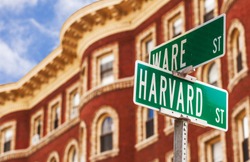 Harvard street sign with a classic red brick building in the background . Location: Harvard University in Cambridge, Massachusetts, USA.
