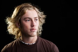portrait of a young caucasian man with long blond hair and striking blue eyes looking to the side in thought