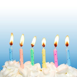 Colorful birthday candles on cake with whipped cream and blue square background