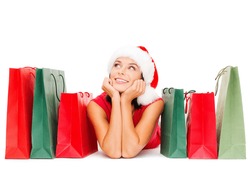 shopping, sale, gifts, christmas, x-mas concept - smiling woman in red shirt and santa helper hat with shopping bags