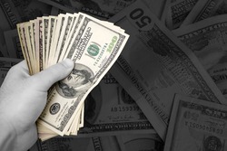 A handful of cash. The money has selective color, and the rest of the image is in black and white - plenty of copy space.