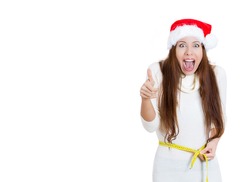 Portrait of Christmas fitness woman excited about weight loss measuring waist with tape wearing santa hat screaming excited showing thumb up, isolated on white background. Positive emotion, expression