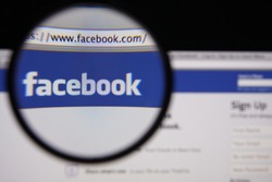 LISBON - JANUARY 14, 2014: Photo of Facebook homepage on a monitor screen through a magnifying glass.