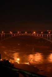 United States - Canada border bridge lit up at night by lights, at Niagara Falls