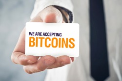 Businessman holding card with title WE ARE ACCEPTING BITCOINS. Selective focus on card and fingers.