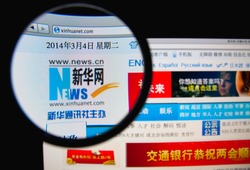 LISBON, PORTUGAL - MARCH 10, 2014: Photo of the Xinhua News Agency homepage on a monitor screen through a magnifying glass.