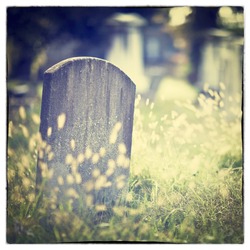 Tombstone and graves in an ancient church graveyard with Instagram style filter effect