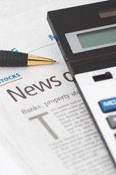 Stocks News, pen, calculator, banks, property headlines, shallow depth of field, vertical orientation