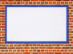Large white blank billboard sign with a blue wooden frame on a red brick wall.