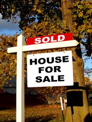 Real estate advertising sold rider insert over home owner house for sale sign on a wood post in a residential neighborhood street