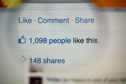 LISBON, PORTUGAL - AUGUST 27, 2014: Photo of Facebook notifications of Likes and Shares on a monitor screen through a magnifying glass.