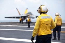 NORFOLK, VA - JUNE 27: Flight deck crew known as Yellow Shirts watch as an F18 is positioned on the deck of the USS Harry S. Truman on June 27, 2014. The aircraft carrier is stationed in Norfolk, VA.