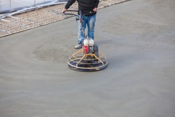 Construction worker produces the grout and finish wet concrete with a special tool. Float blades. For smoothing and polishing concrete, concrete floors
