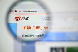 LISBON, PORTUGAL - NOVEMBER 17, 2014: Photo of Sina Weibo homepage on a monitor screen through a magnifying glass.