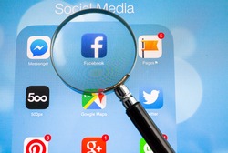 BANGKOK FEBRUARY 26, 2015: Facebook being magnified on tablet. Facebook is an online social networking service headquartered in Menlo Park, California.