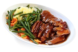 Platter of sliced roast beef with gravy, mashed potatoes, string beans and carrots. A hearty meal.