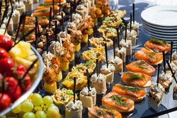 Catering service plate .appetizing sandwiches on plastic sticks rangeSandwiches on a table the buffet. meat, fish, vegetable canapes on a festive wedding table outdoor