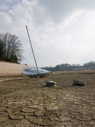 Effect of global warming: a boat on the bottom of a dry lakebed. Dried, cracked earth is the consequence of the climate change and global warming.