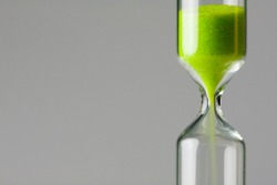 Diminishing green. Ecology / environment concept image. Green sand of hour glass falling down.