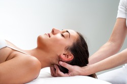 Close up of chiropractor pressing back of head. Therapist doing healing massage with fingers at back of neck.