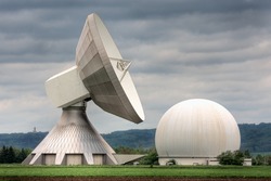 An earth station satellite installation with ancillary building - the type used for broadcasting. Poor weather.