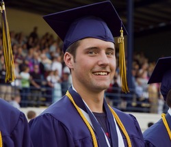 Male high school graduate smiling at the camera during the graduation progression