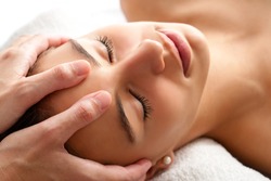 Close up head shot of Woman having curative facial massage. Therapist applying pressure with thumbs on forehead.