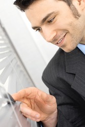 Closeup of happy curious businessman looking out the window through rolling shutter, smiling.