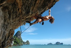 Adult climbing hard overhanging wall in Krabi, Thailand.