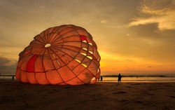 Silhouette of man is preparing para sailing at the sunset beach in Thailand