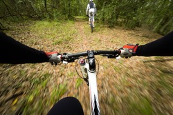 POV, Original point of view. Couple of cyclist during a mountain bike race in the forest.