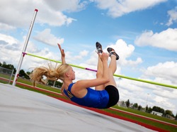 A young, athlete clearing the bar during a high jump event, in track and field.