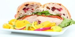 Turkey, mayo, lettuce, tomato on cranberry roll. On plate with yellow beet salad on side.